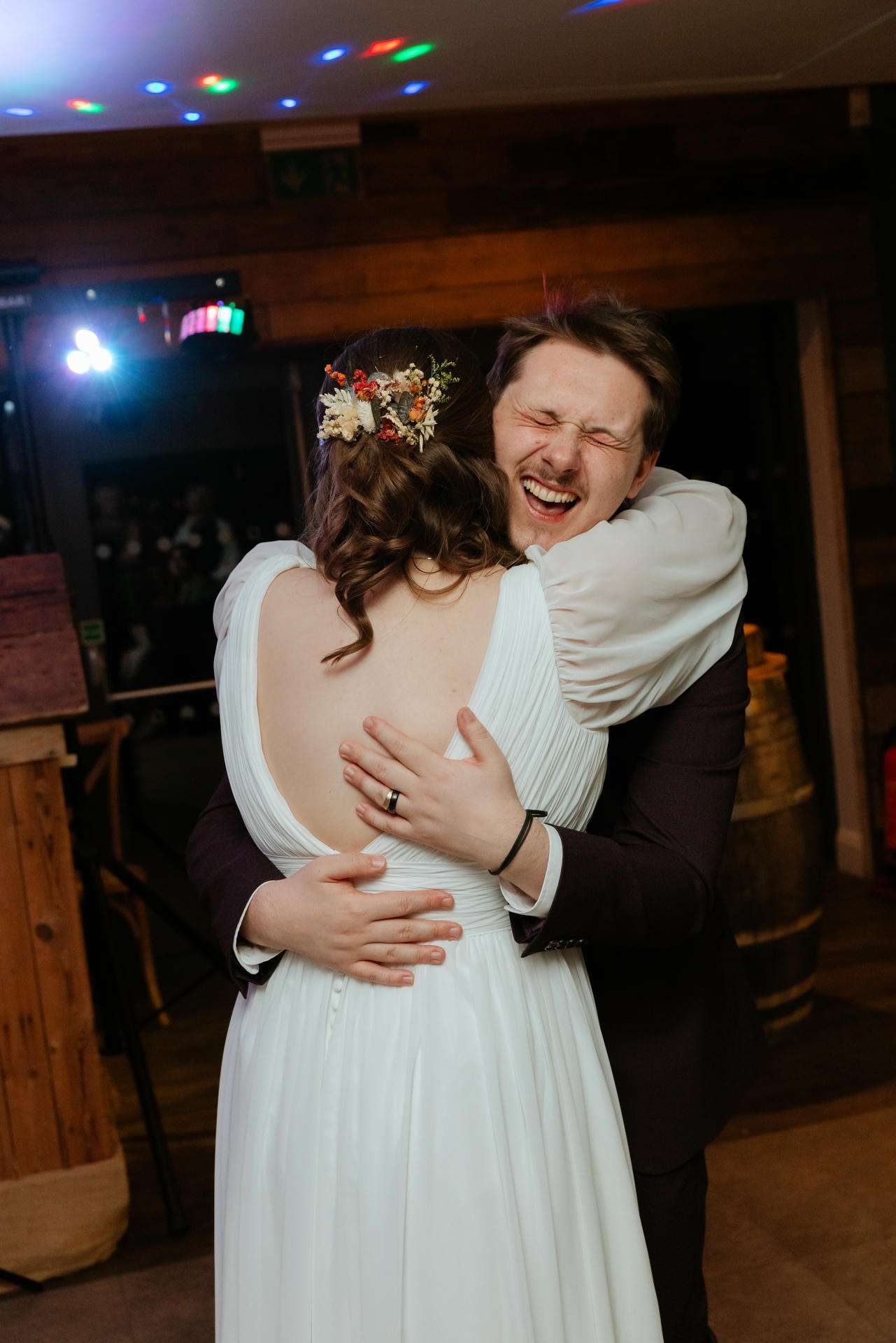 A bride and groom share a joyful hug at their wedding reception.