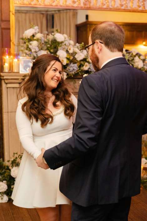 A couple dancing at a wedding reception, the woman in a white dress and the man in a dark suit.