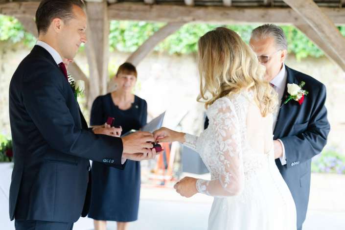 wedding ring exchange Bride and groom exchange rings during an outdoor wedding ceremony.