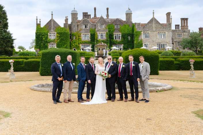 ivy covered manor wedding Wedding party posing in front of an ivy-covered historic manor with a central fountain.