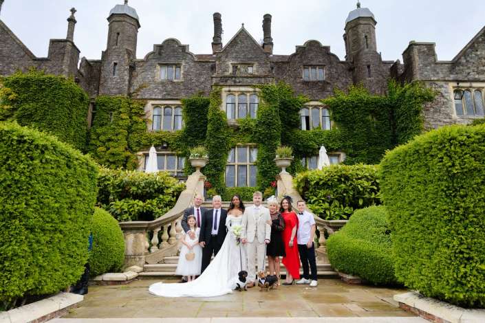 ivy-covered castle wedding Bride and groom pose with their wedding party on the ivy-covered stone staircase in front of a historic mansion.