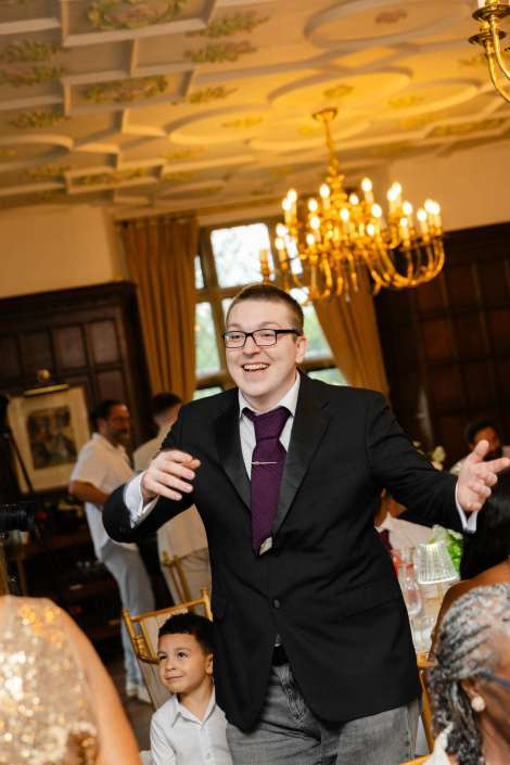 smiling man dancing at gala Smiling man in a dark suit and purple tie dances at a formal banquet as a young boy watches nearby.