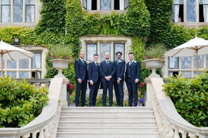 groomsmen on ivy covered staircase Five groomsmen in navy suits with green ties pose on a stone staircase in front of an ivy-covered building.