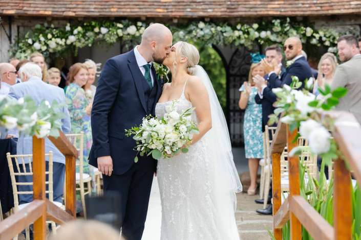 romantic outdoor wedding kiss Bride and groom kiss at their outdoor wedding as guests applaud along the aisle.