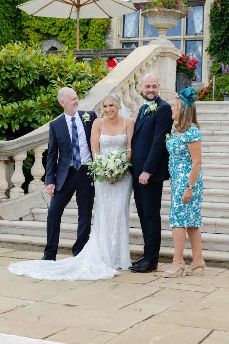 wedding party on stone staircase Bride in a white wedding gown holding a bouquet stands with her groom and two guests on an outdoor stone staircase.