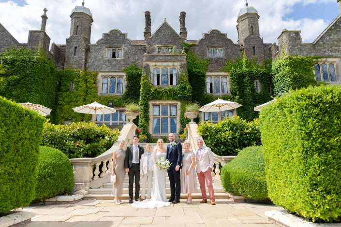 ivy covered castle wedding Wedding party posing on a stone staircase in front of an ivy-covered, castle-like stone building.