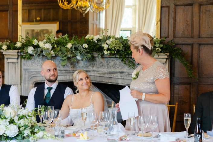 bride and groom at wedding table Bride and groom listening to a wedding speech at an elegant top table decorated with white floral arrangements.
