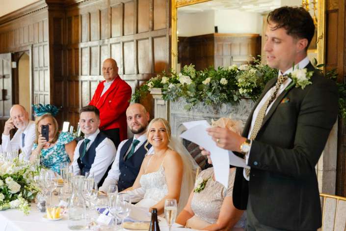 wedding speech at head table Best man giving a speech at a wedding reception top table as the smiling bride and guests listen.