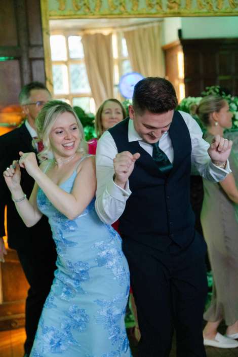 couple dancing at wedding reception Smiling woman in a light blue dress and a man in a vest dancing happily at a wedding reception.